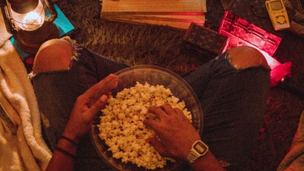 Person enjoying popcorn while watching Stranger Things in a cozy room setup.