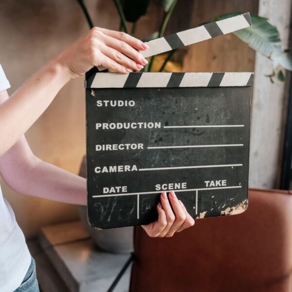 Close-up of hands holding a film slate board in an artistic indoor setting.