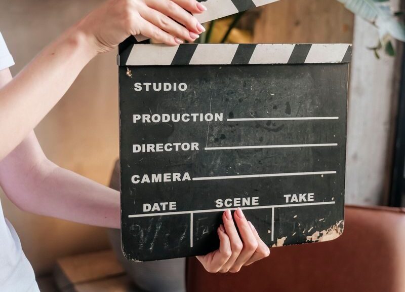 Close-up of hands holding a film slate board in an artistic indoor setting.