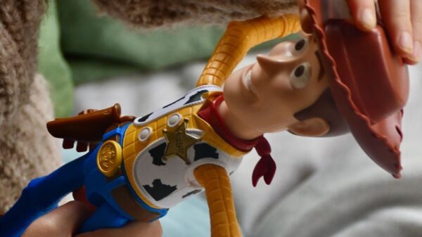 Child's hand holding a cowboy doll indoors, showing playtime fun.