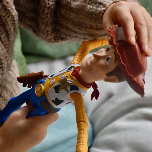 Child's hand holding a cowboy doll indoors, showing playtime fun.