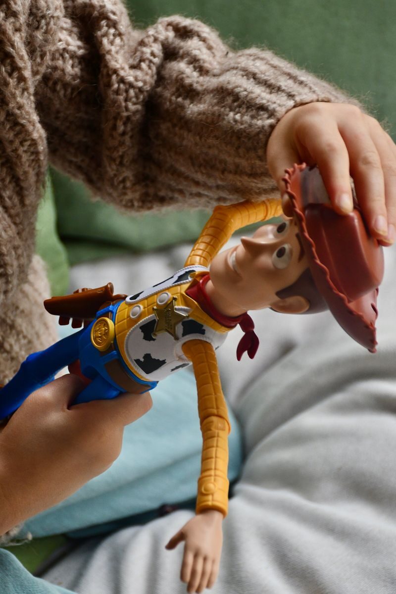 Child's hand holding a cowboy doll indoors, showing playtime fun.