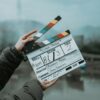 Close-up of a film clapperboard on an outdoor set, signaling scene start.