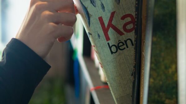 A hand reaches for a book on a shelf, bathed in soft lighting indoors.