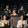 Audience watching film in theater, enjoying popcorn in a cozy setting.