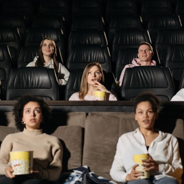 Audience watching film in theater, enjoying popcorn in a cozy setting.
