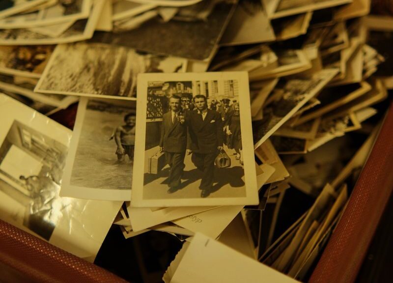 A collection of vintage black and white photographs in an antique suitcase.