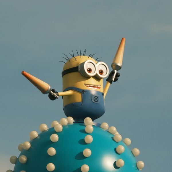 Vibrant Minion character statue atop a whimsical spiked orb under a clear blue sky.