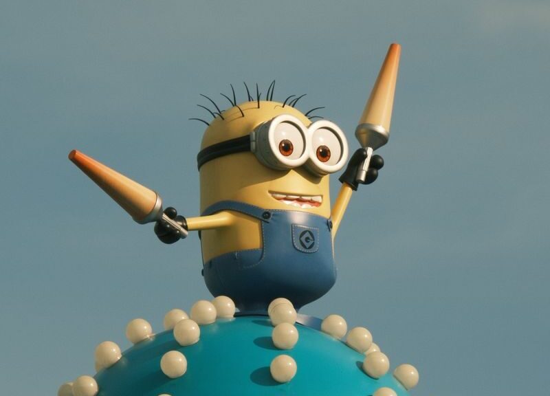 Vibrant Minion character statue atop a whimsical spiked orb under a clear blue sky.