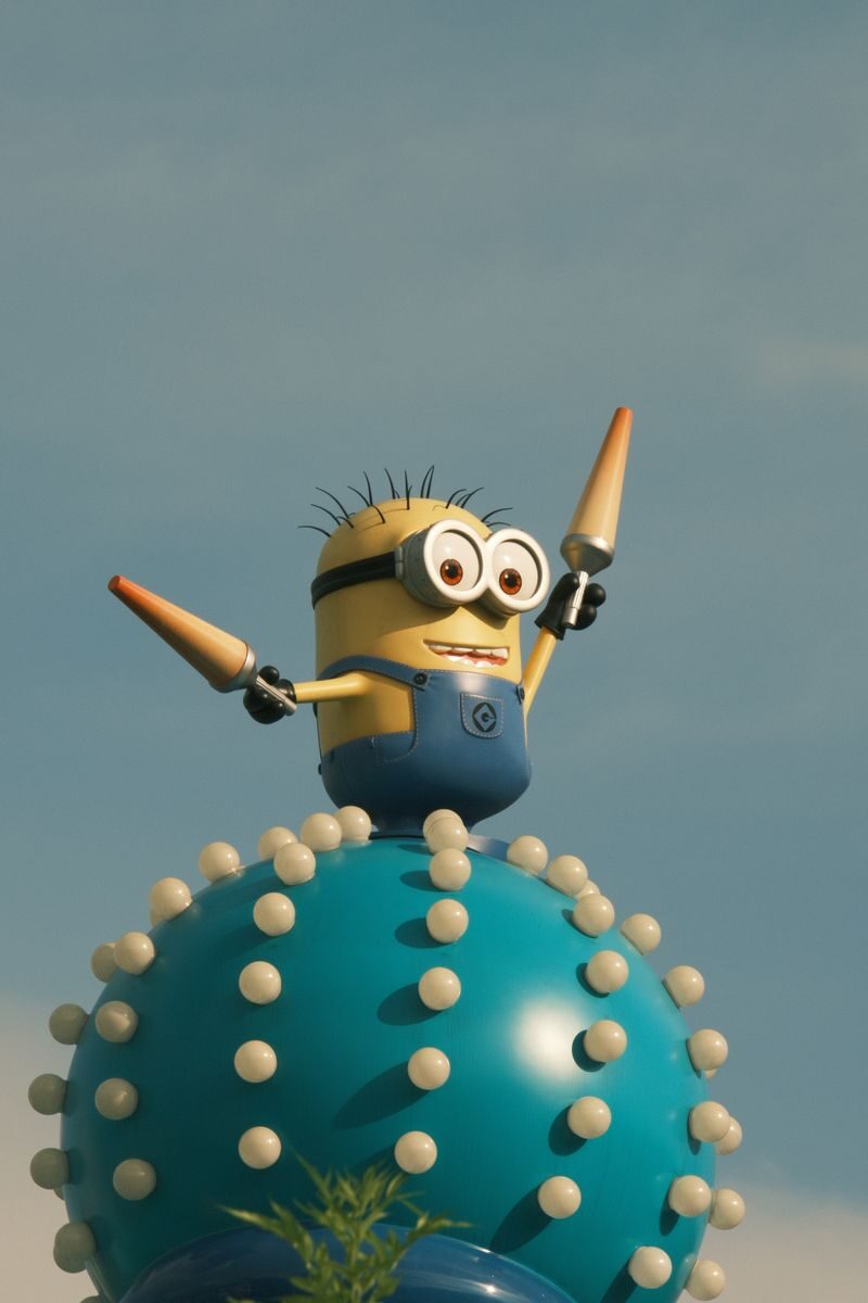 Vibrant Minion character statue atop a whimsical spiked orb under a clear blue sky.