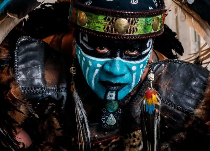 Vibrant tribal costume featuring face paint, feathers, and intricate details.