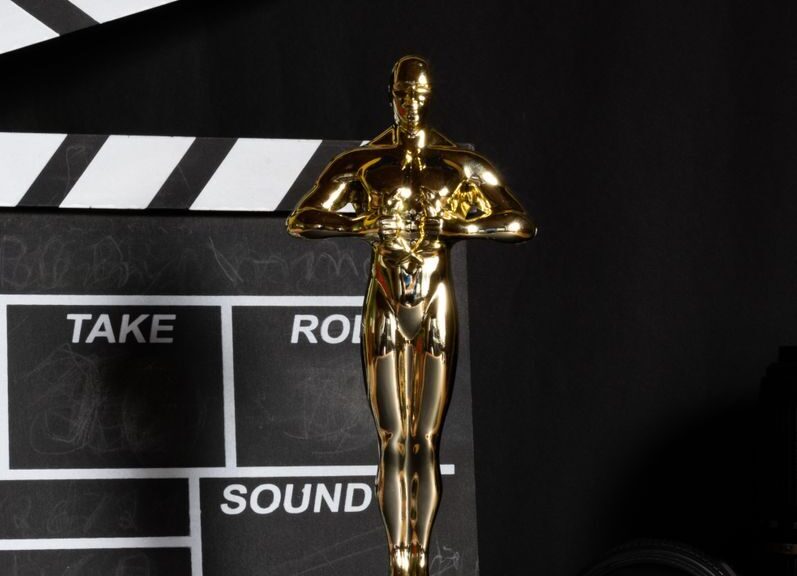 A golden trophy next to a film clapperboard symbolizes cinema success and achievement.