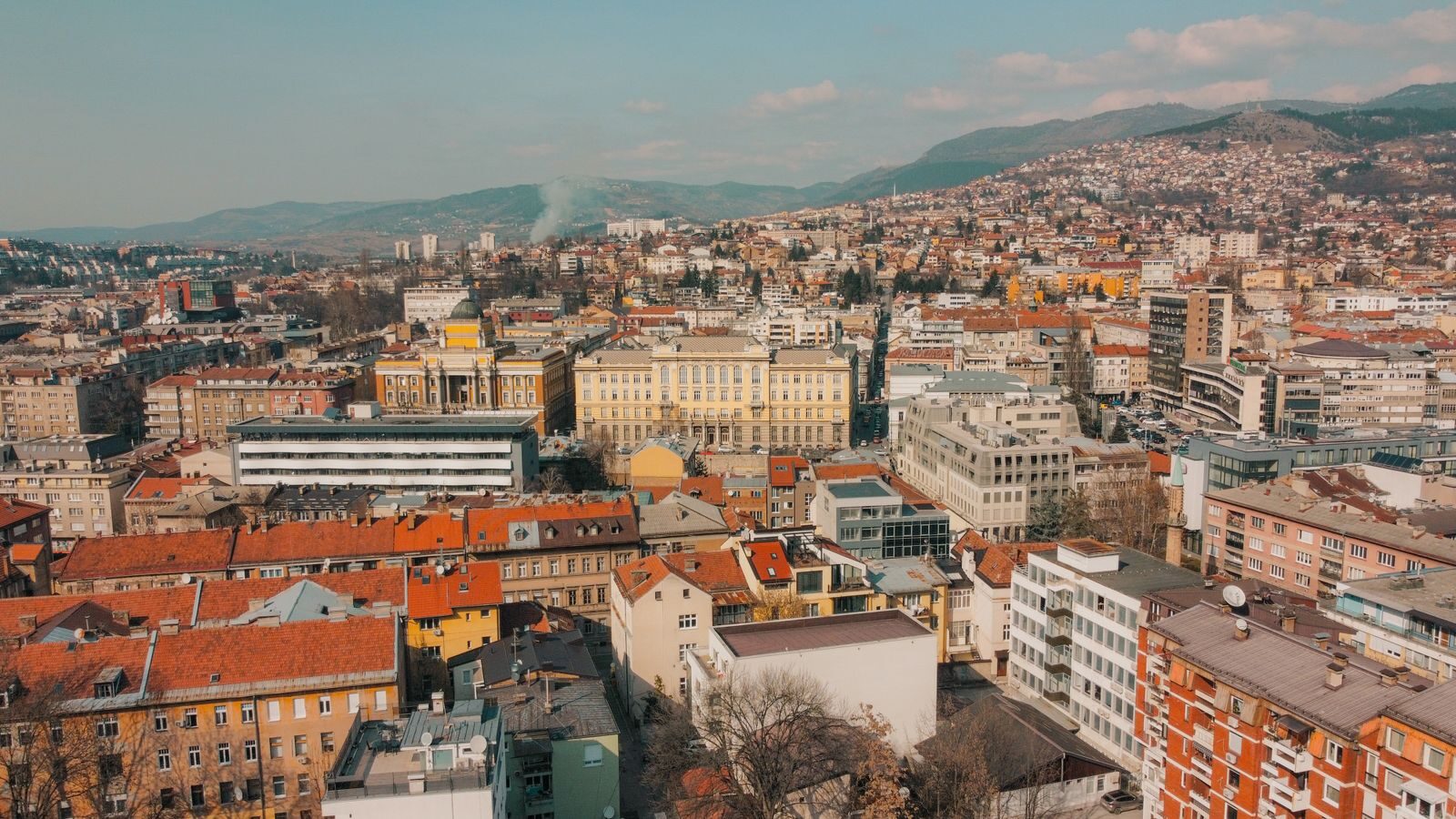 Aerial view of Sarajevo's sprawling cityscape with historic architecture and hills.