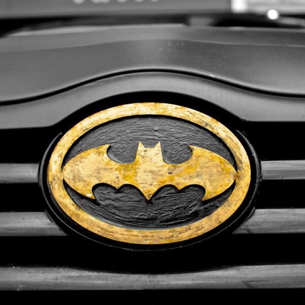 A detailed image of the iconic Batman logo on a car's grill, highlighting superhero symbolism.