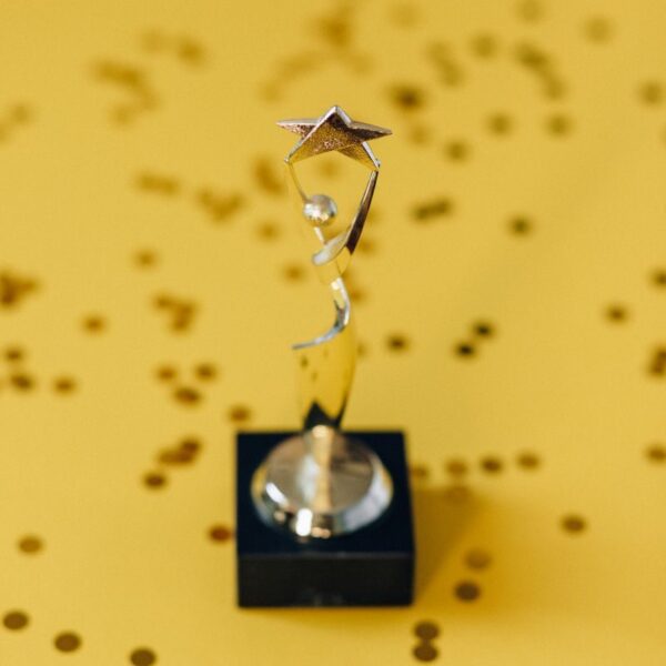 Silver star trophy on yellow background with confetti. Perfect for success concepts.