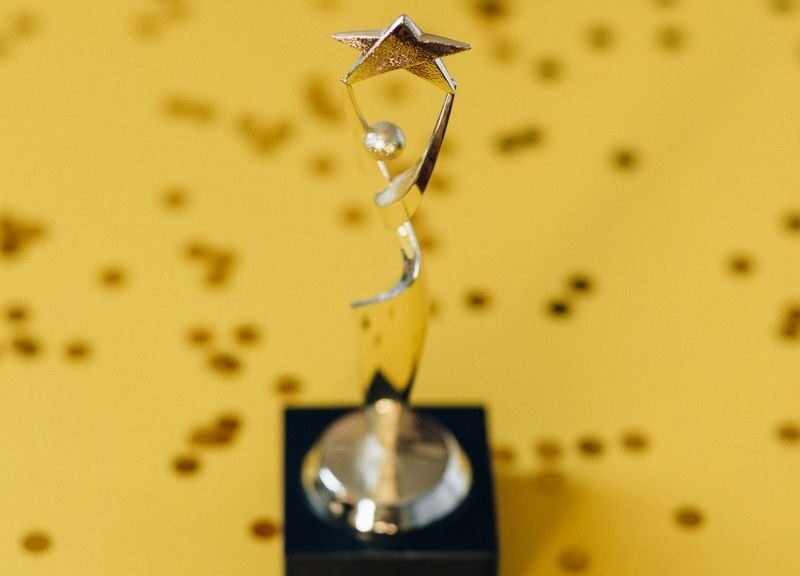Silver star trophy on yellow background with confetti. Perfect for success concepts.