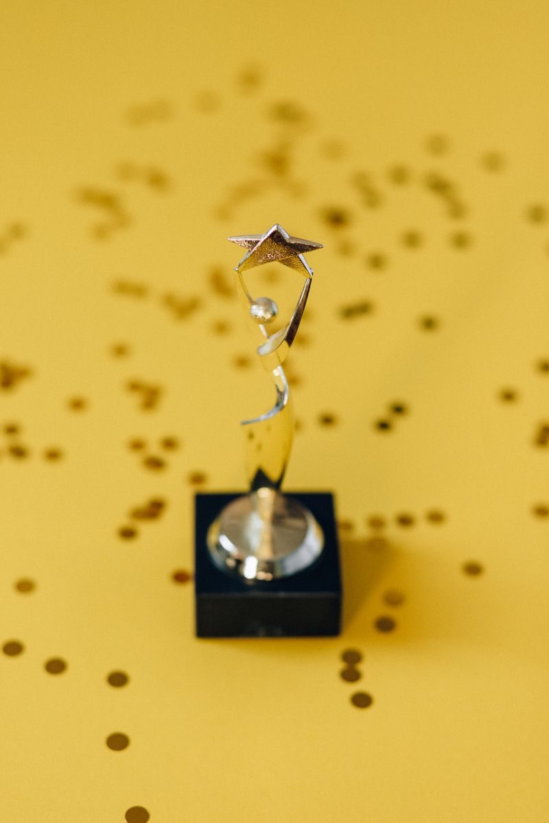 Silver star trophy on yellow background with confetti. Perfect for success concepts.