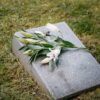 White lilies placed on a gravestone in a serene cemetery setting.