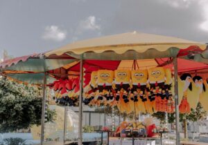 A vibrant fairground stall with plush toys including popular characters on display under a canopy.