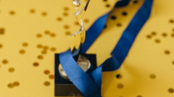 A golden trophy and medal with blue ribbon on a confetti-strewn yellow surface, symbolizing victory and achievement.
