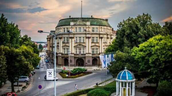 A historic building in Niš, Serbia, under a dramatic cloudy sky, showcasing elegant architecture.