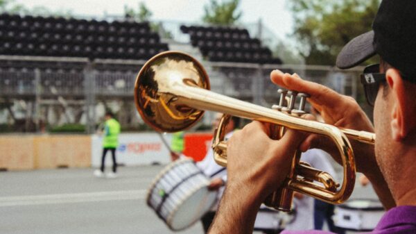 A man plays the trumpet outdoors during a lively festival parade.