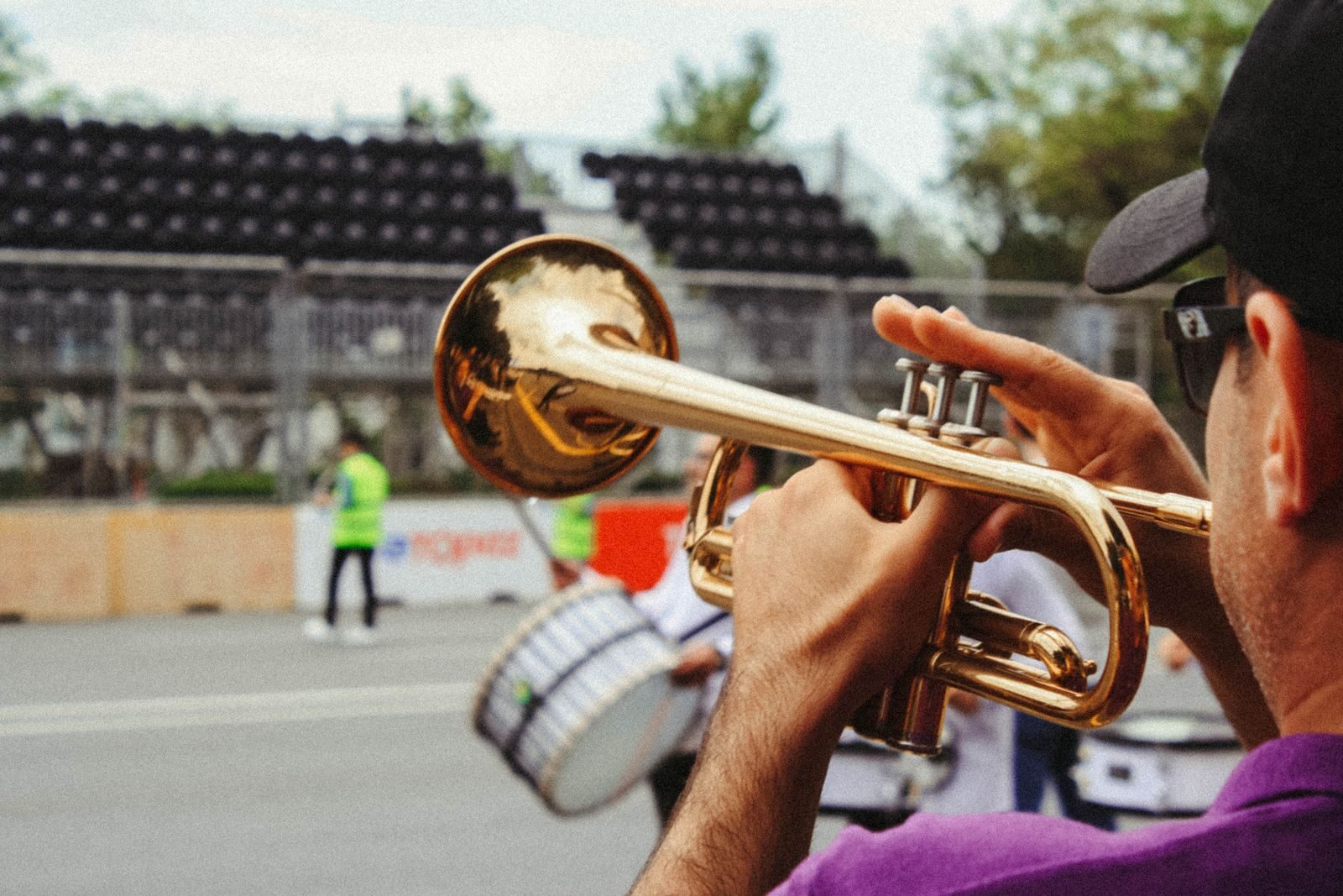 A man plays the trumpet outdoors during a lively festival parade.
