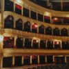 Luxurious opera house interior featuring ornate gold designs and red velvet balconies.