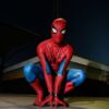 A person in Spider-Man costume crouching outdoors at night, poised for action.