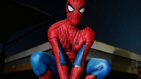 A person in Spider-Man costume crouching outdoors at night, poised for action.