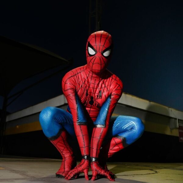 A person in Spider-Man costume crouching outdoors at night, poised for action.