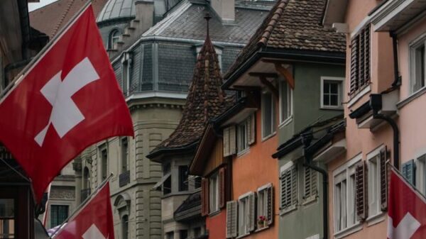 Colorful street in Zurich adorned with Swiss flags under a cloudy sky, showcasing Swiss culture and architecture.