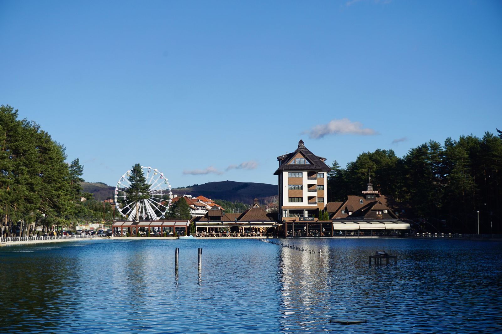 Serene lake view in Zlatibor, Serbia, featuring a Ferris wheel and vibrant landscape, perfect for travel imagery.