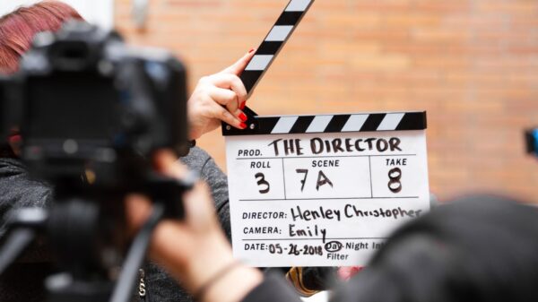 Close-up of film clapperboard in action with camera filming a take on set.