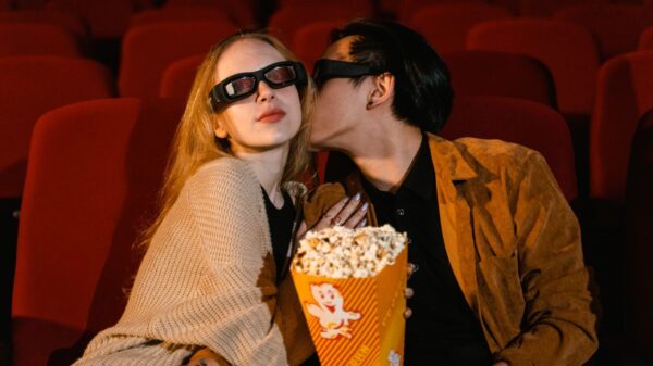 Young couple enjoying a movie date with popcorn in a theater, wearing 3D glasses.