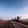 Open highway on a frosty winter morning with clear blue skies and distant billboards.