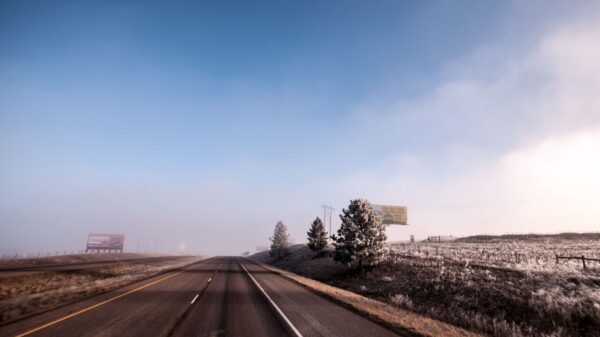 Open highway on a frosty winter morning with clear blue skies and distant billboards.