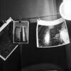 Monochrome photos drying on a line in a darkroom, showcasing photography development.