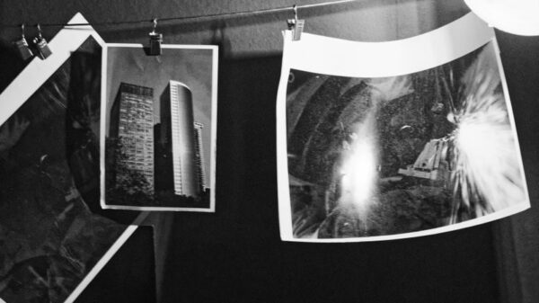 Monochrome photos drying on a line in a darkroom, showcasing photography development.