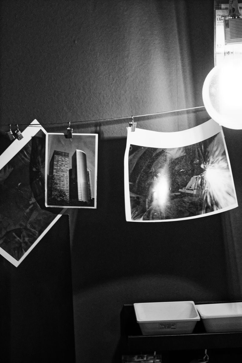 Monochrome photos drying on a line in a darkroom, showcasing photography development.