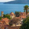 Aerial view of a charming Mediterranean village by the sea with red tiled roofs.