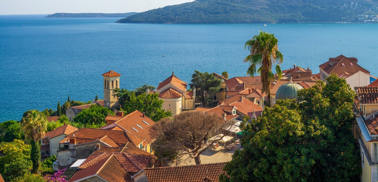 Aerial view of a charming Mediterranean village by the sea with red tiled roofs.