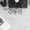 Flat lay of a music workspace with a laptop, headphones, turntable, and speakers on a desk.