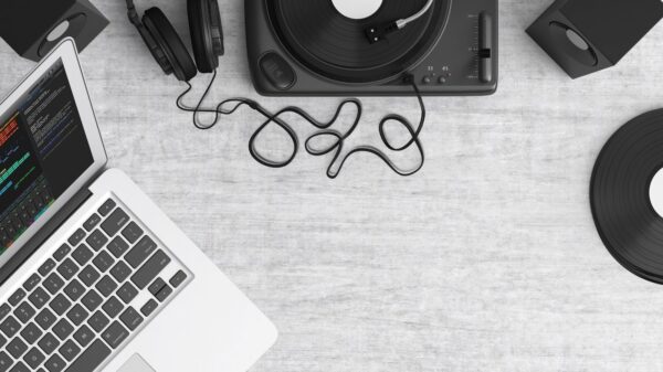 Flat lay of a music workspace with a laptop, headphones, turntable, and speakers on a desk.