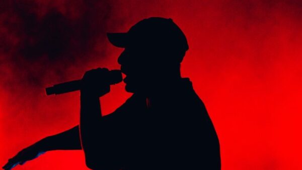 Silhouette of a performer singing on stage with striking red and black lighting.