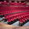 Empty theater with red seats and balcony, perfect for events and performances.