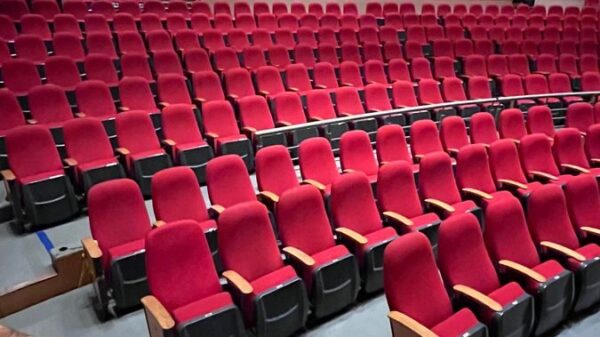 Empty theater with red seats and balcony, perfect for events and performances.