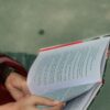 Close-up of hands holding an open book outdoors in Khulna, Bangladesh. Peaceful reading moment.