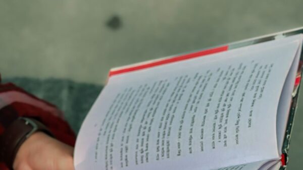 Close-up of hands holding an open book outdoors in Khulna, Bangladesh. Peaceful reading moment.