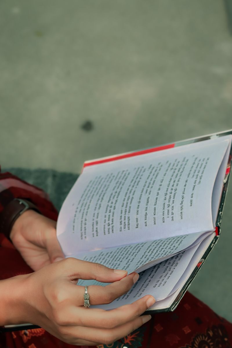 Close-up of hands holding an open book outdoors in Khulna, Bangladesh. Peaceful reading moment.